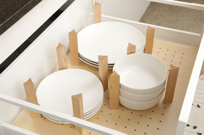 A white drawer with wooden dividers, containing four white plates and three white bowls.