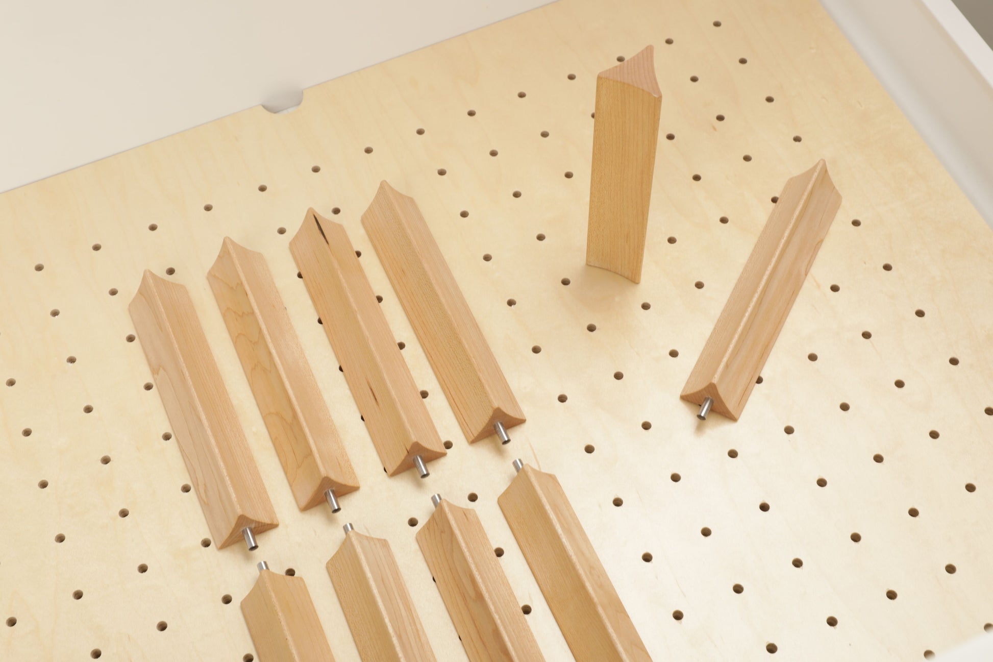 a wooden pegboard with several wooden blocks or wedges attached to it, arranged in a grid-like pattern.