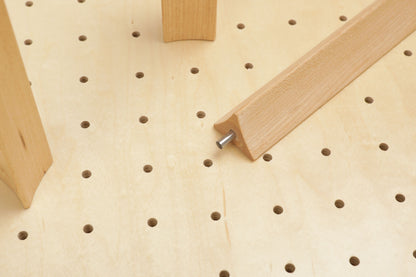 a wooden board with a hole in it, and a wooden piece is inserted into the hole, creating a connection between the two.