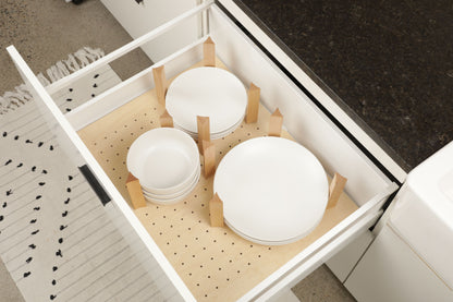 A white drawer with a wooden organizer holding several white plates and bowls.